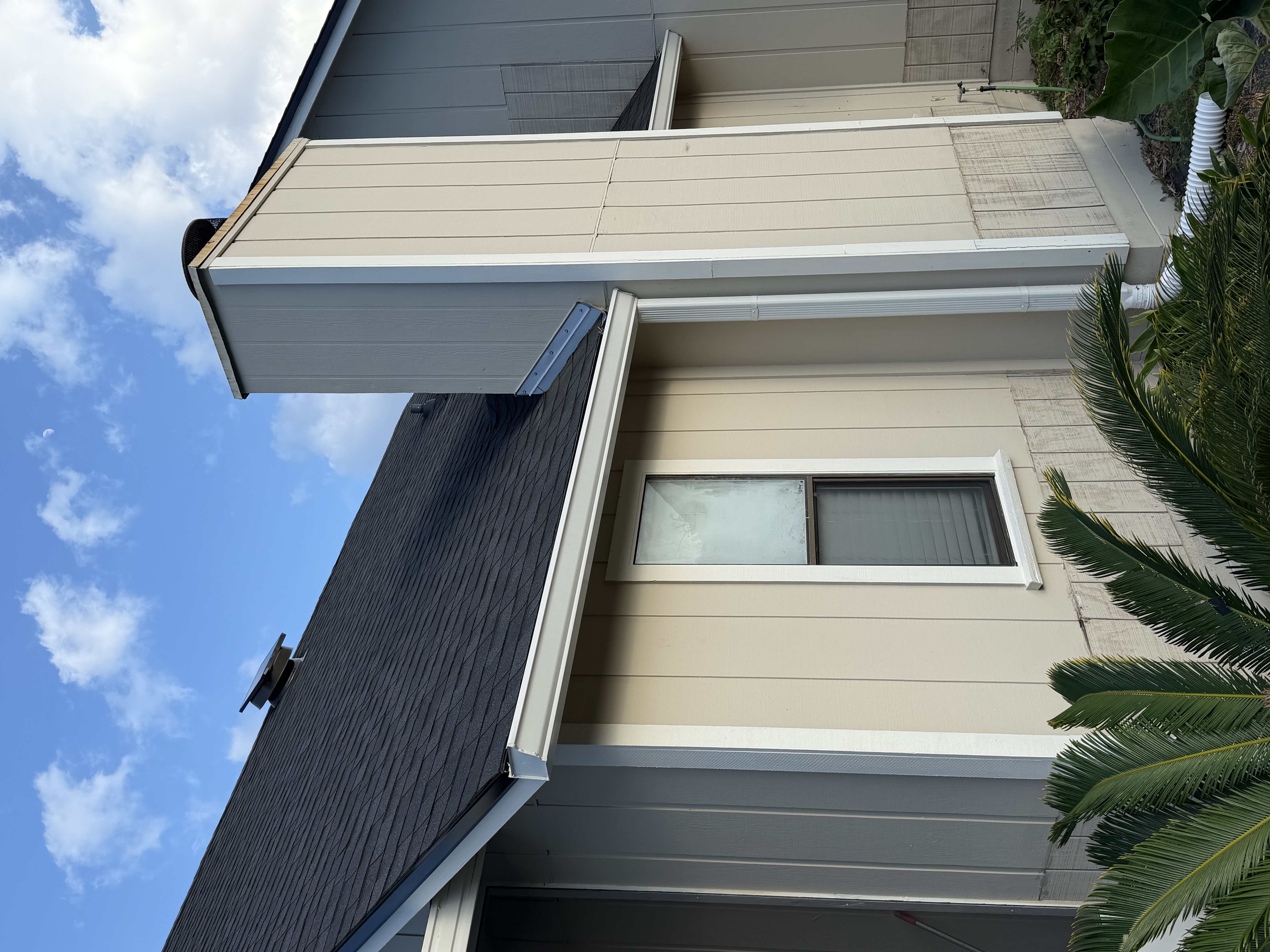 Close-up of new white seamless gutter fitted along a two-story home eave